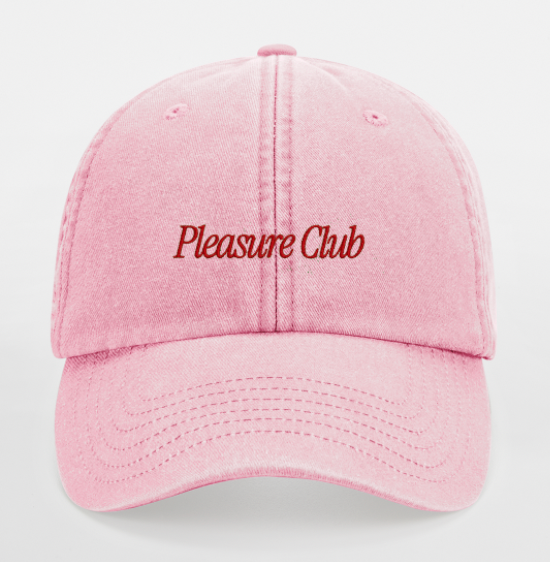 Pink cap with 'Pleasure Club' text on a light gray background