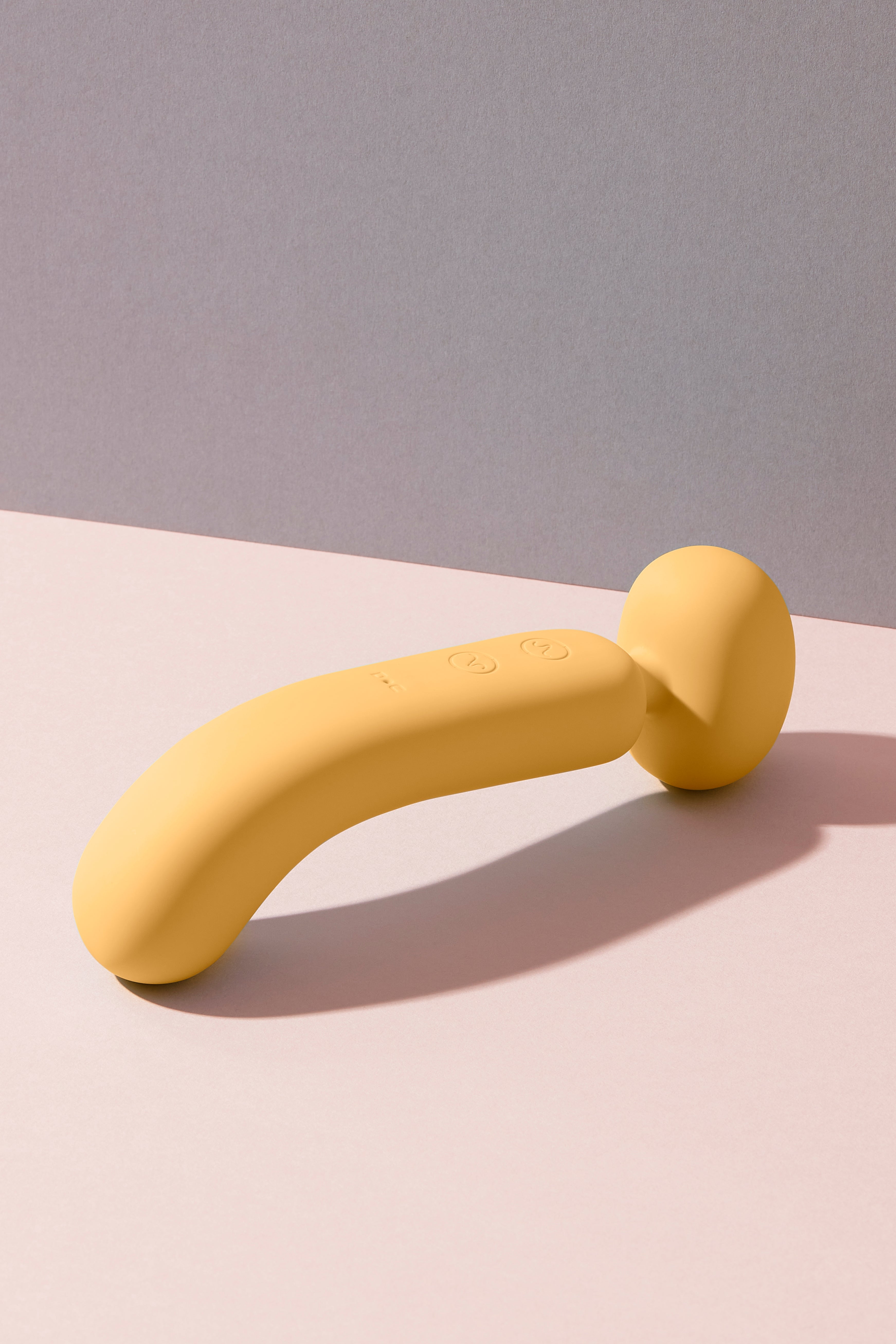 A dual-ended yellow wand massager with a smooth, curved design, made from soft silicone material.