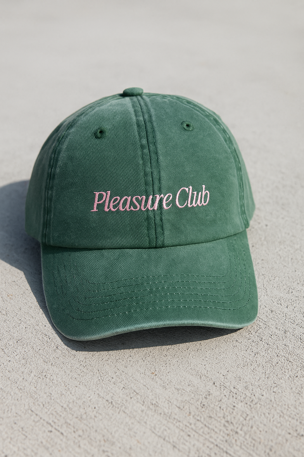 Green cap with 'Pleasure Club' text on a light gray background